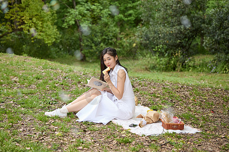 户外年轻女性坐在草坪上看书图片