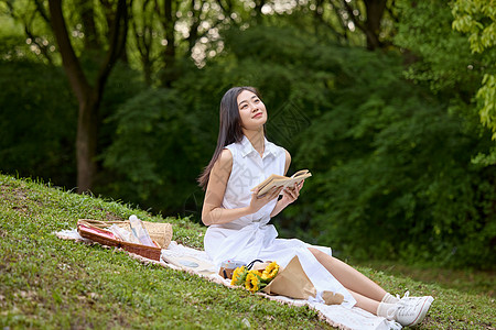 户外草坪上拿着书本的美女形象图片