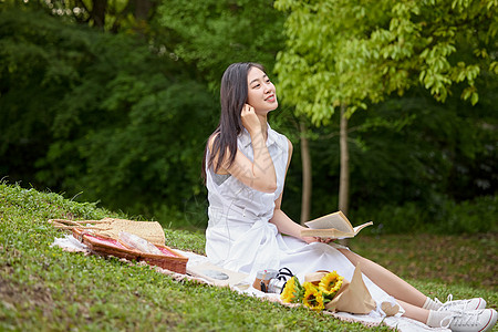 年轻女性在森林公园的草地上看书图片