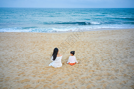 坐在沙滩上的海边母女背影图片