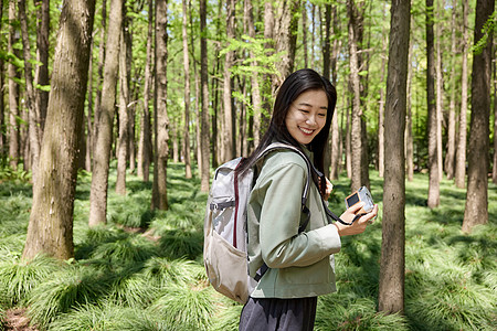 森林里背包拿相机的女性图片