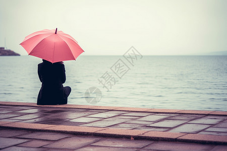 打着伞坐在海边的人图片