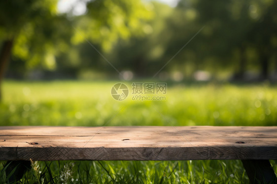 公园草坪上的模糊木桌背景图片