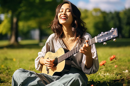 草坪上演奏吉他的年轻女子图片