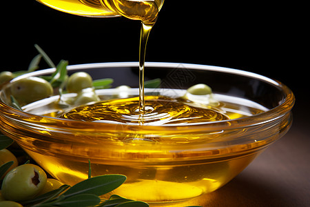 橄榄油洒在带叶的装有橄榄的碗中背景图片