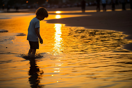 海滩上夕阳下的小男孩图片