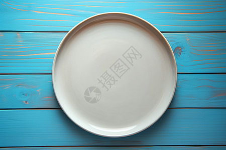蓝色木质桌上的一只白色盘子图片