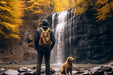 秋季瀑布下的小狗与男子图片