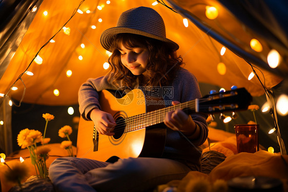 夜晚帐篷中演奏吉他的女孩图片