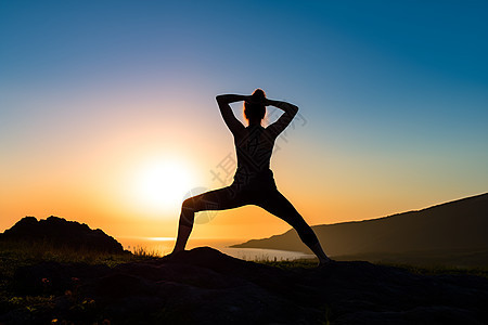 日出山谷中瑜伽锻炼的女子图片