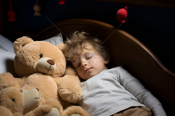 床上的小男孩和玩具熊图片