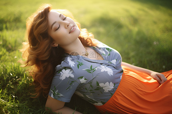 草坪上躺着闭着眼睛微笑的女子图片