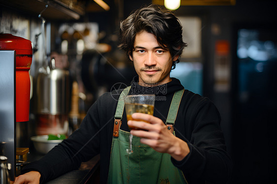 穿着绿色围裙的男人，端着一杯啤酒图片