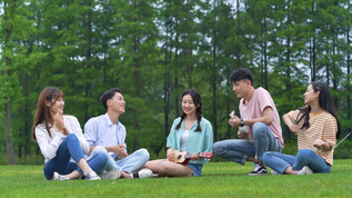 4k青年开心的坐在草坪上聚会唱歌视频素材