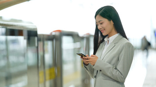 4k在地铁站内使用手机等待地铁的女性白领视频素材