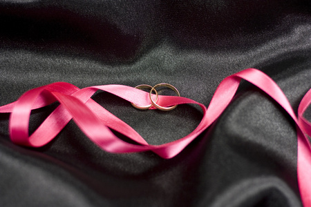 两个结婚戒指，粉红色丝带