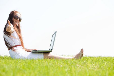 一位年轻女性在公园里用笔记本电脑