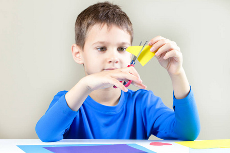 男孩用剪刀在桌切割彩色的纸