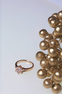 庆祝的的装饰品。用石头和束人造花的金戒指。在白色背景上