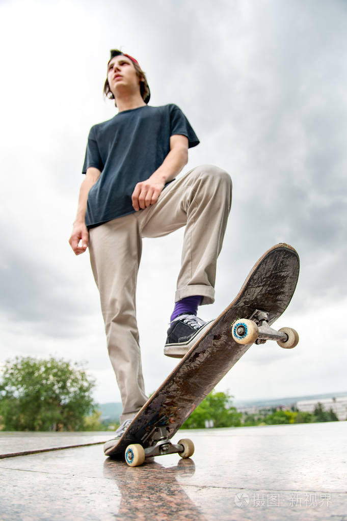 一个年轻的溜冰者站在滑板上的城市景观的背景