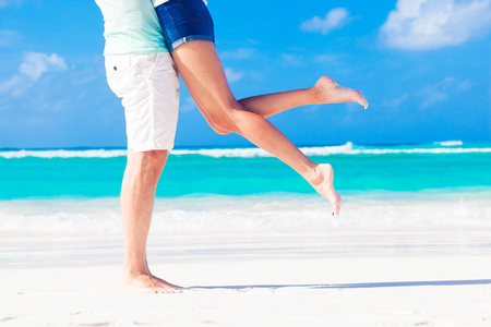 腿的年轻接吻情侣热带绿松石加勒比海滩上照片