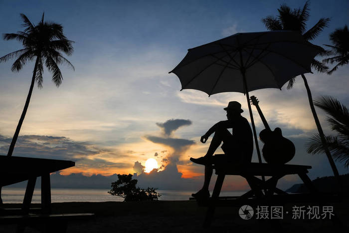 在海滩上蓝蓝的天空日出弹吉他的男人