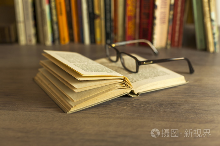 老本打开的书,在图书馆的桌子上的眼镜