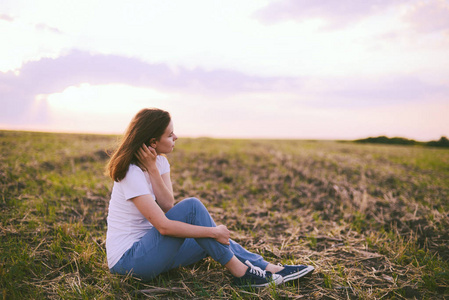 年轻女人放松在夏季室外的夕阳的天空。人考