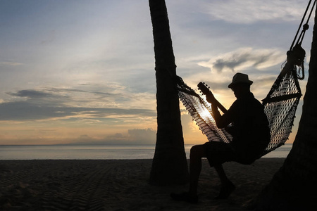 在沙滩上与夕阳弹吉他的男人照片