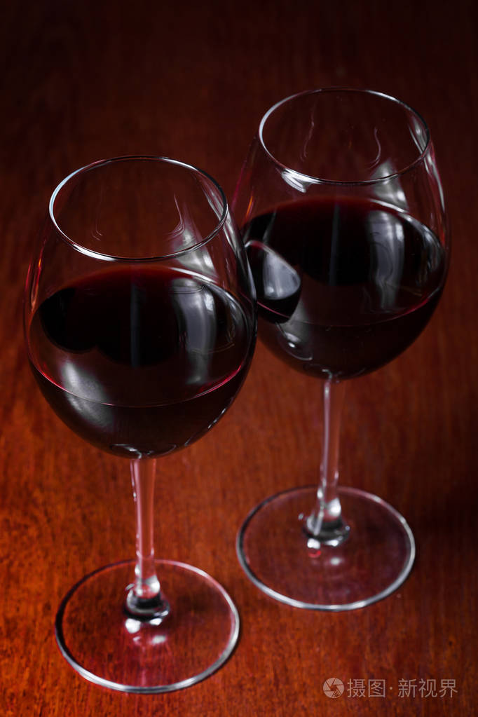 两杯红葡萄酒在黑暗的背景上照片