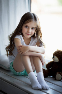 一个漂亮的女孩，与一只棕色玩具熊的肖像