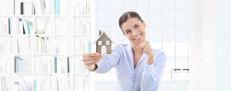 家的概念微笑的女人显示房子模型 房地产和
