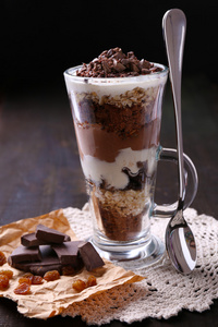 酸奶 奶油夹心巧克力 切碎的巧克力和牛奶什锦早餐服务在玻璃上木制的背景