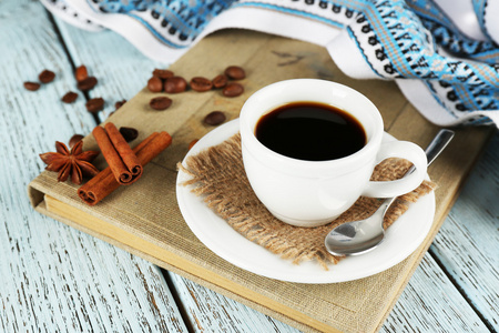 杯咖啡上颜色木制背景与桌布 八角茴香 咖啡豆和肉桂书