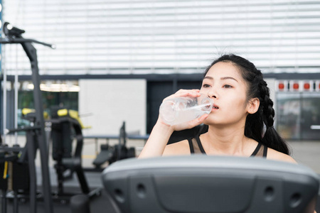 年轻女人喝水中健身中心。女运动员费