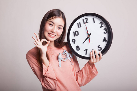 年轻的亚洲女人与时钟显示确定