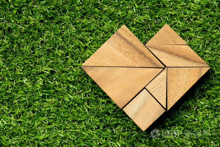 木质七巧板拼图上人工绿色心脏形状中的草 bac