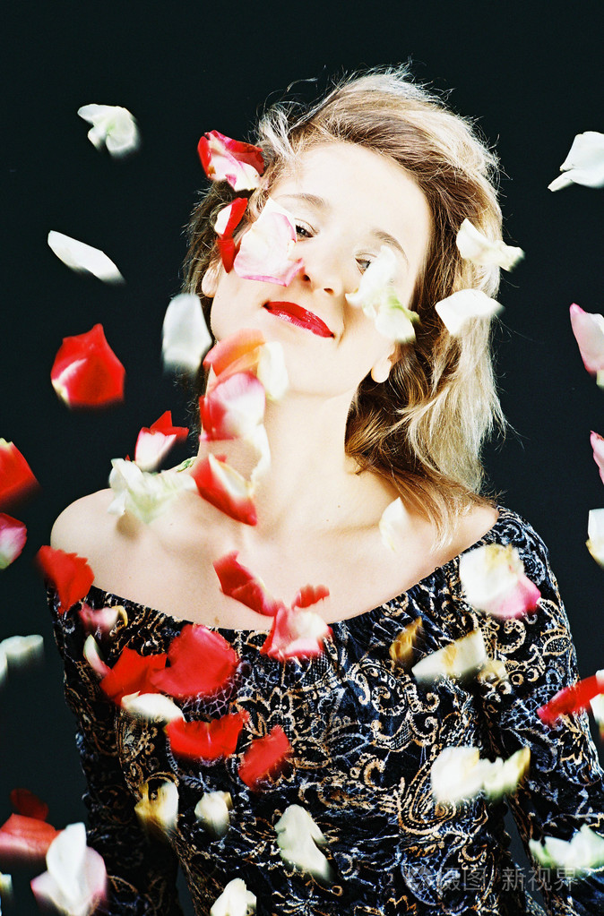 美丽的女孩躺在玫瑰花瓣上