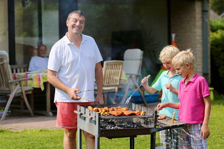 父亲与孩子准备上在花园里烧烤的肉