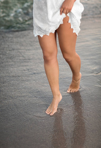 完美女人的腿上沙的海滩和大海的水。海水与沙滩上女人的腿。完美清洁女性的脚