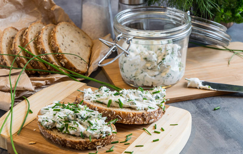 家庭面包用凝乳干酪 意大利乳清干酪和香草的木菜板上。装饰着绿色的香草