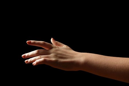 在黑暗背景下的女性手女性从黑暗中伸出手花环,圆环框架与棉花花的