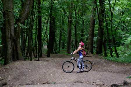 年轻女孩在夏天在林中骑自行车运动磨损