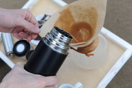 为替代酿造咖啡在沙滩上托盘上的配件。从热水瓶倒了咖啡在筛选器中