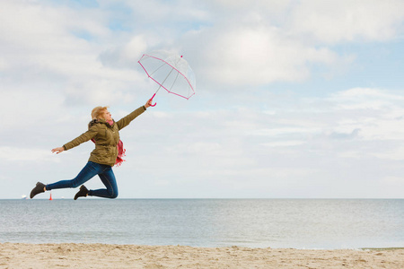 在海滩上跳跃着透明雨伞的女人