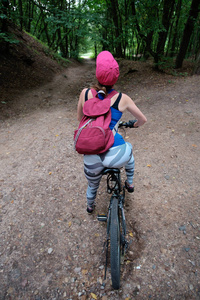 年轻女孩在夏天在林中骑自行车运动磨损