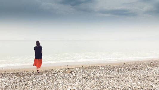 年轻女子独自在赤脚走在海岸边