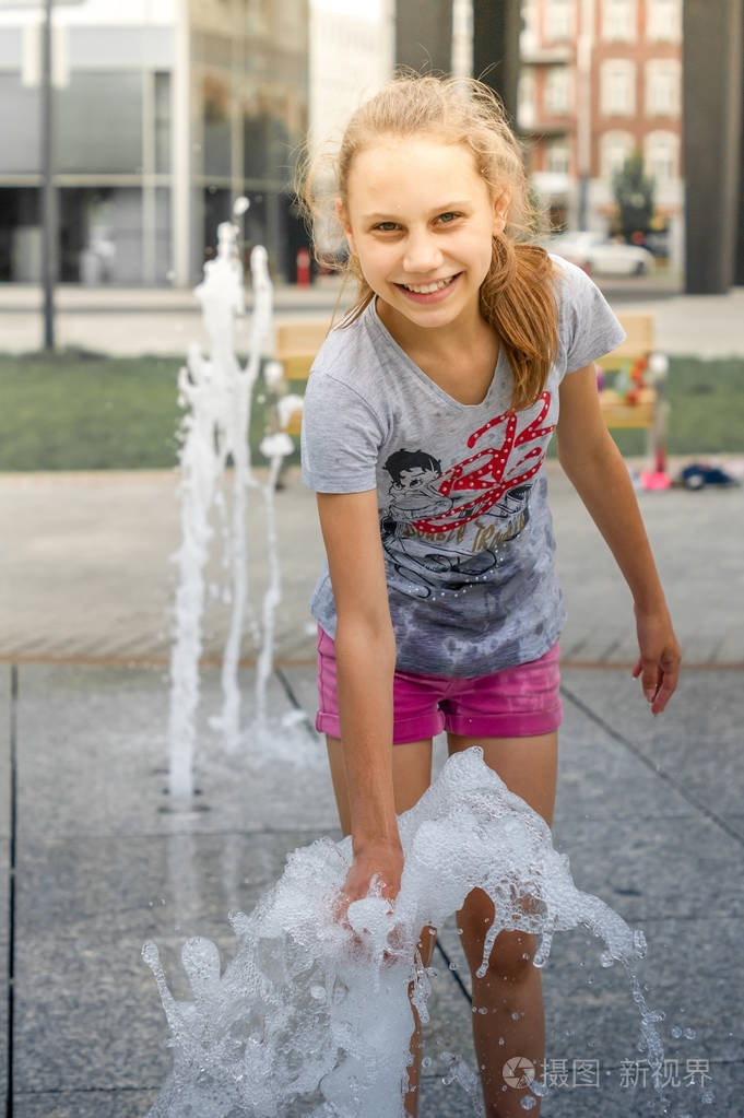 女孩子站在喷泉喷喷射的水流