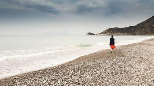 年轻女子独自在赤脚走在海岸边