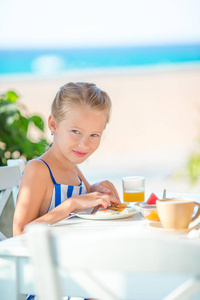 可爱的小女孩，在清晨海景咖啡馆吃早餐